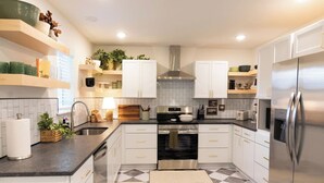 Une cuisine moderne avec des meubles blancs, un réfrigérateur en acier inoxydable et un carrelage à motifs.