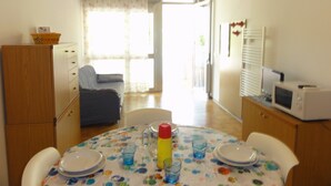 A small dining area with a table set for two, a microwave, and a refrigerator. - Cozy Apartment With Private Entrance (San Michele al Tagliamento)