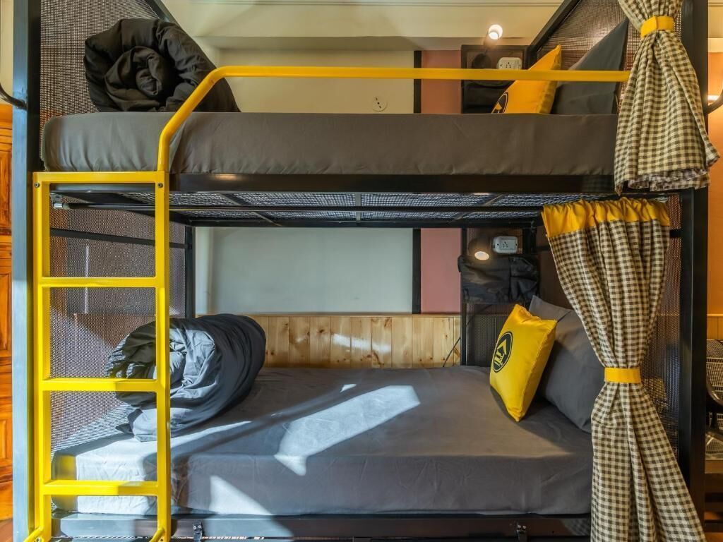 A bunk bed room with a ladder, a pillow, and a curtain.