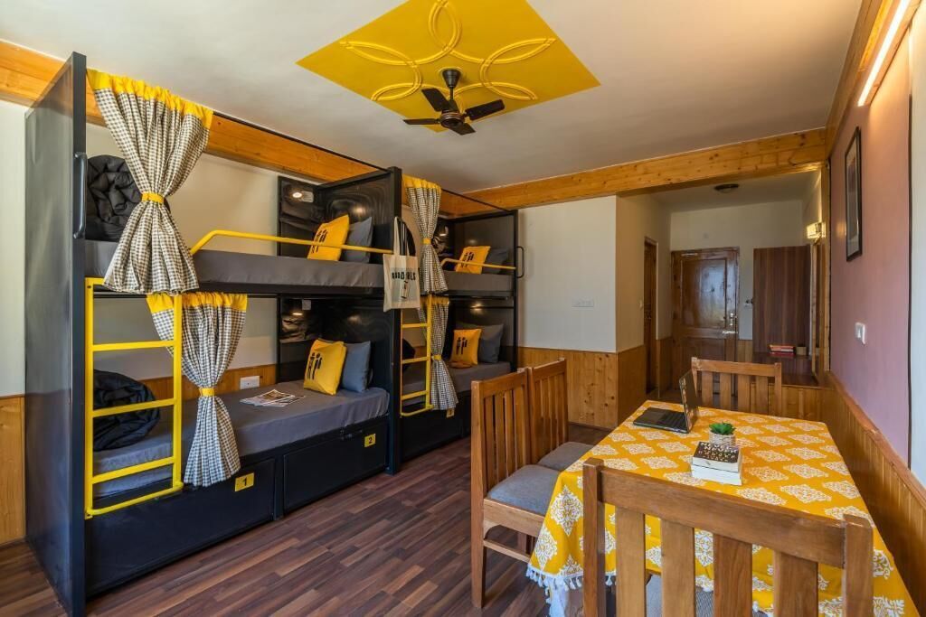 A compact room with bunk beds, a dining table, and a ceiling fan.