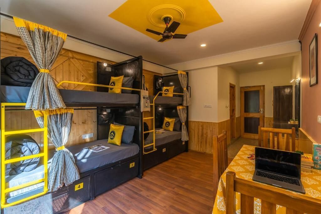 Una habitación con literas, un escritorio con una computadora portátil y un ventilador de techo.