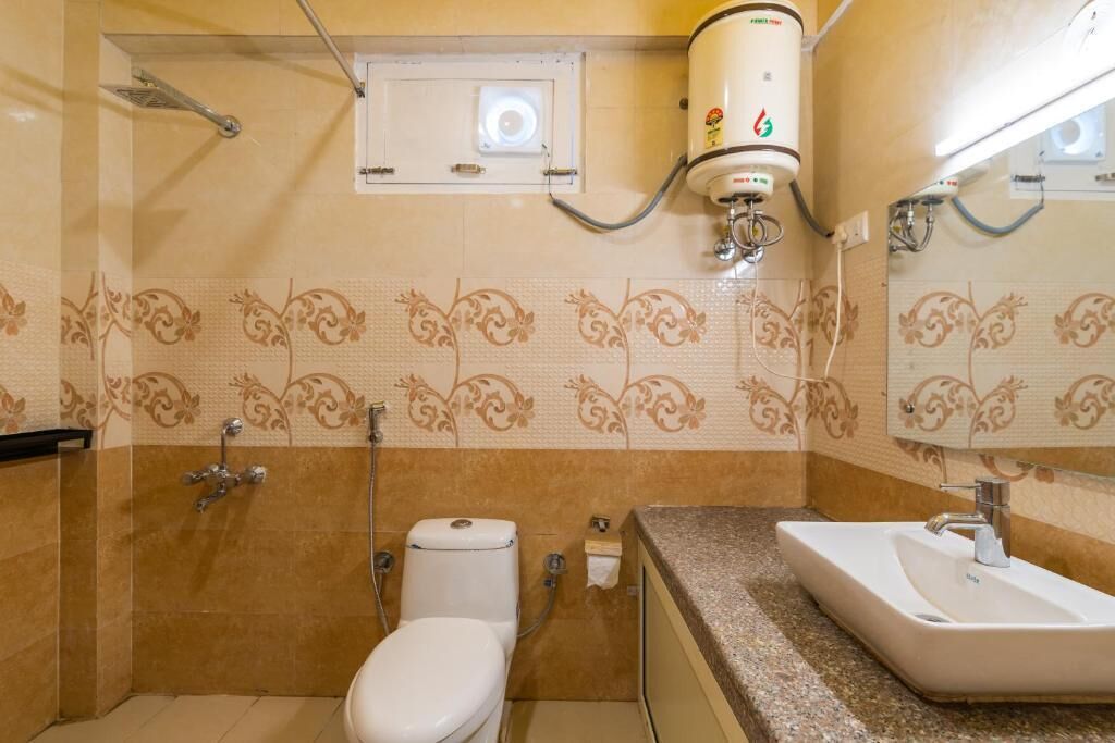 A bathroom with a toilet, sink, shower, and a water heater mounted on the wall.