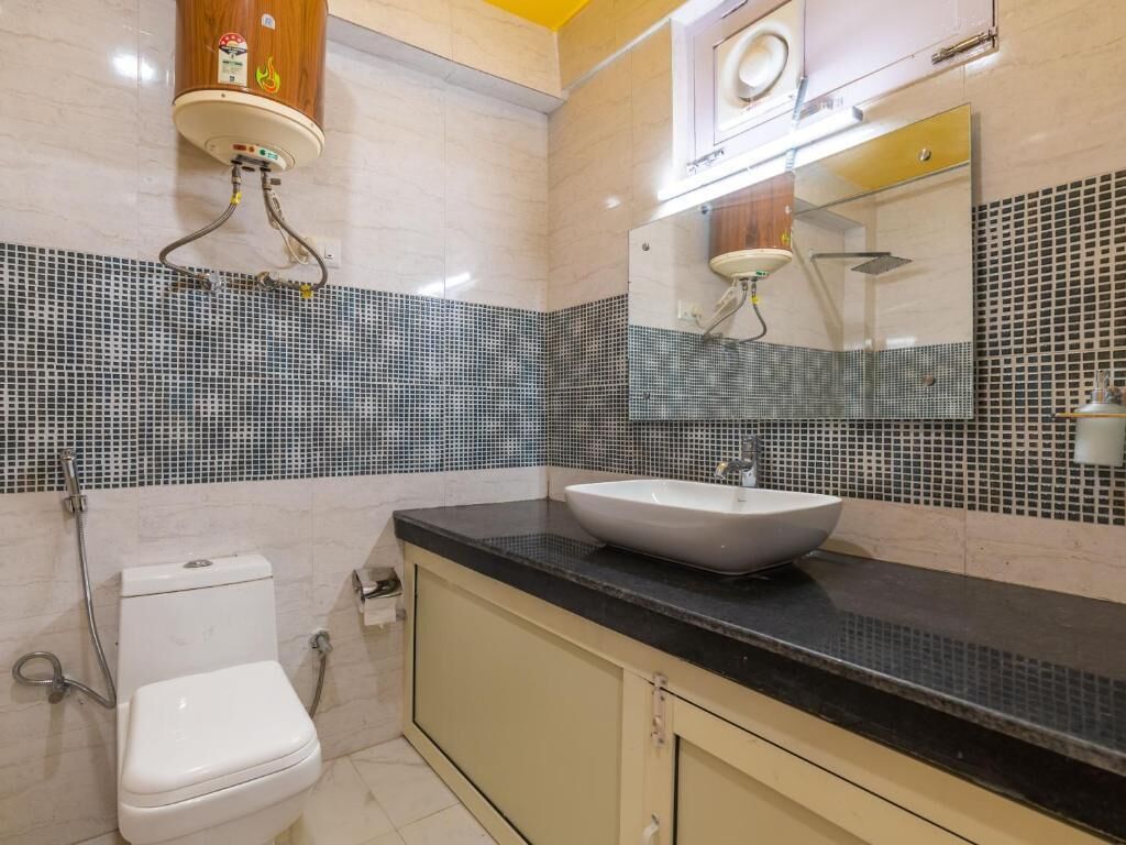 A bathroom with a toilet, sink, and mirror.