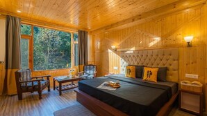Een houten kamer met een bed, een stoel, een tafel en een raam.