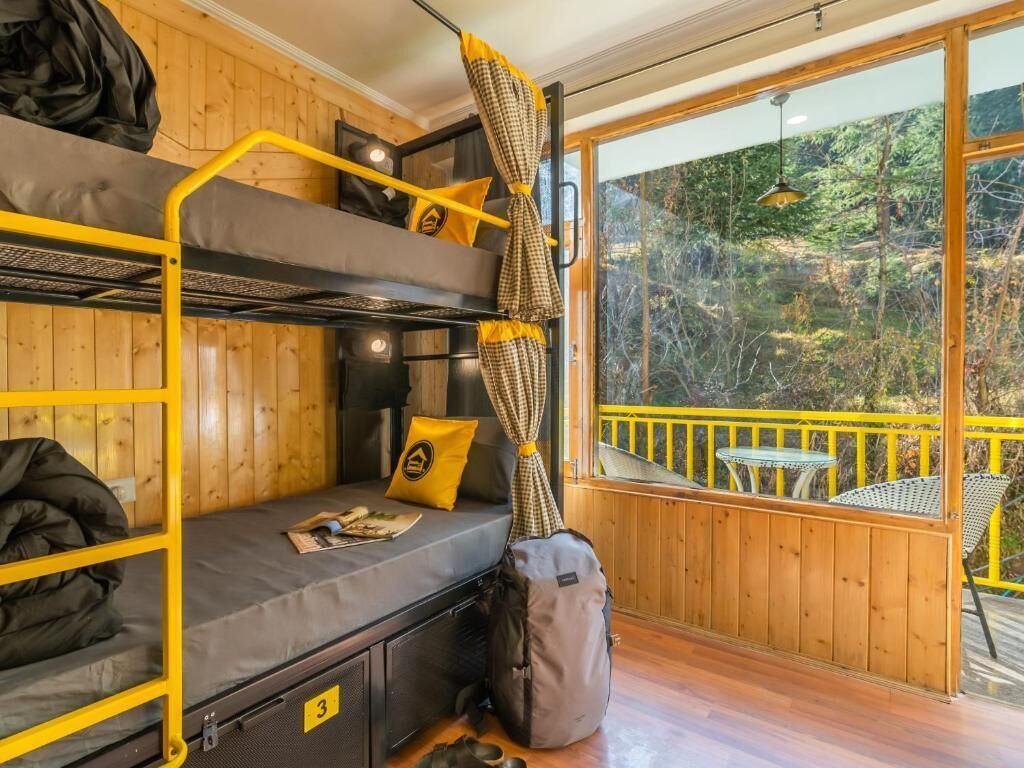 Une chambre avec des lits superposés donnant sur une terrasse en bois et un espace verdoyant.