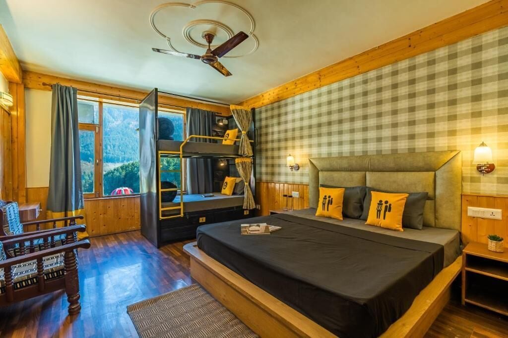 Une pièce confortable avec un lit superposé, un canapé, un bureau et une vue sur les montagnes.