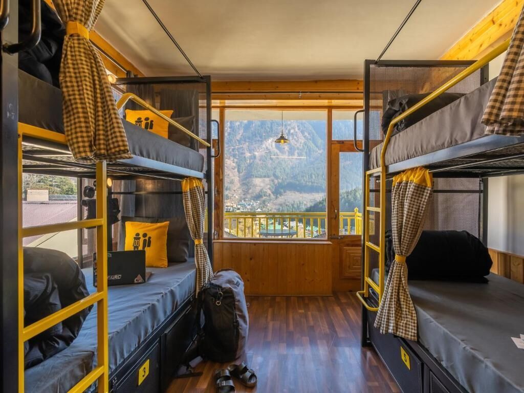 Ein kleines Zimmer mit Etagenbetten, einem Laptop und Blick auf eine Berglandschaft.