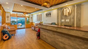 Een hotel receptie met een houten vloer, een receptiebalie en een groot raam met uitzicht op de omgeving.