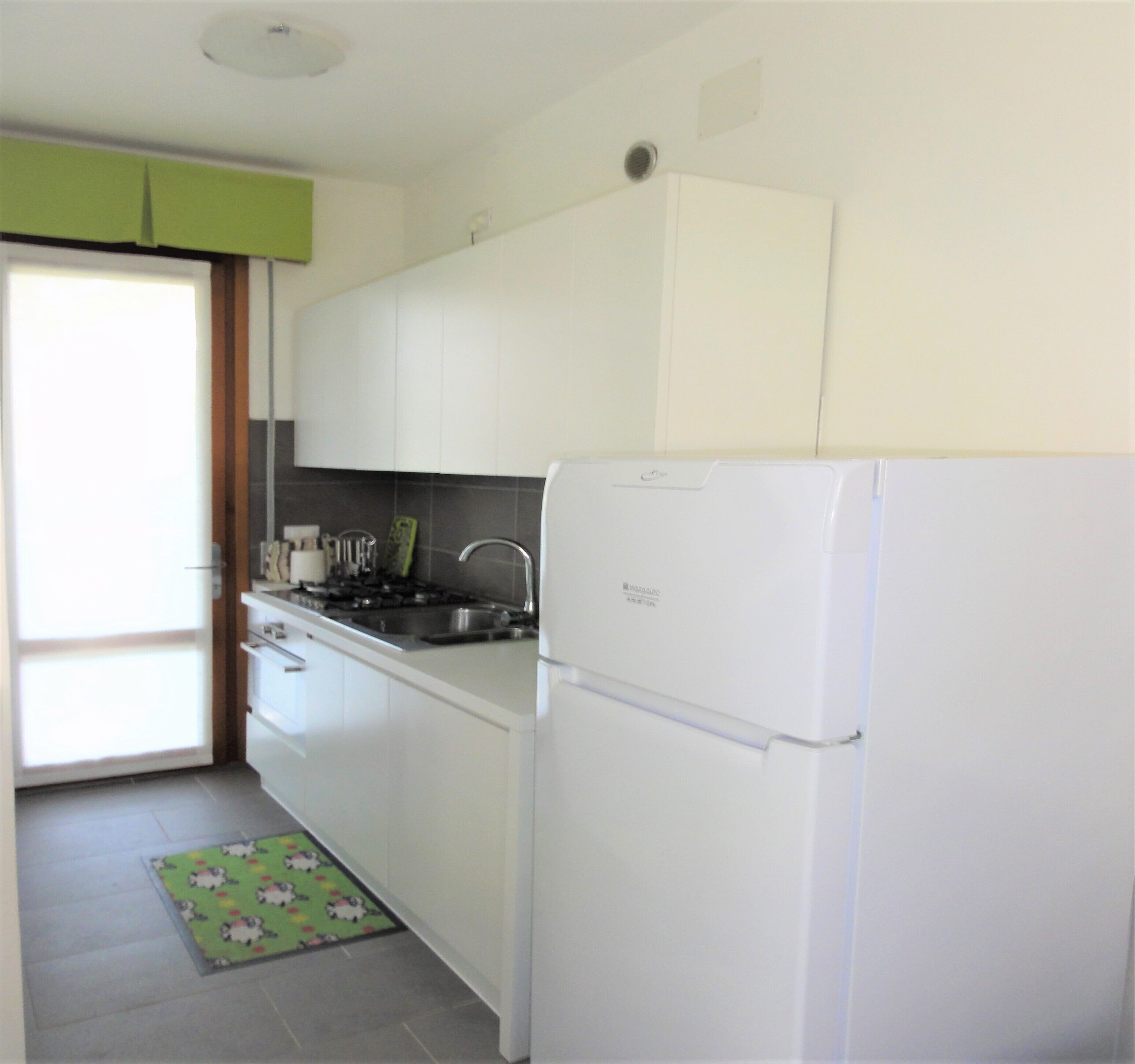 A compact kitchen with white cabinets, a built-in stove, and a white refrigerator.