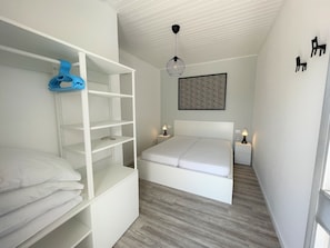 A bedroom with a bunk bed, a bedside table, a hanging light fixture, and a wall art piece. - Bright Duplex Apartment Near Beach (San Michele al Tagliamento)