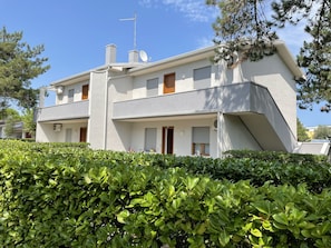 Un moderno edificio residenziale a due piani con tetto piatto, parabola satellitare e un piccolo balcone.