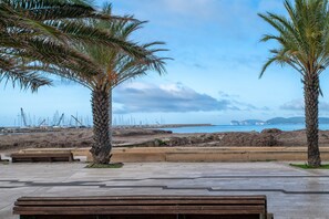 A coastal promenade with palm trees, benches, and a view of the sea and distant ships. - Piera's Apartment In Alghero – Steps from the Seafront, Ideal for Couples and Families (Alghero)