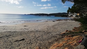 A beach with a clear sky, calm sea, and distant land. - Piera's Apartment In Alghero – Steps from the Seafront, Ideal for Couples and Families (Alghero)