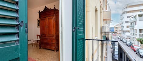 Un balcon donnant sur une rue, un meuble en bois et un sol carrelé.