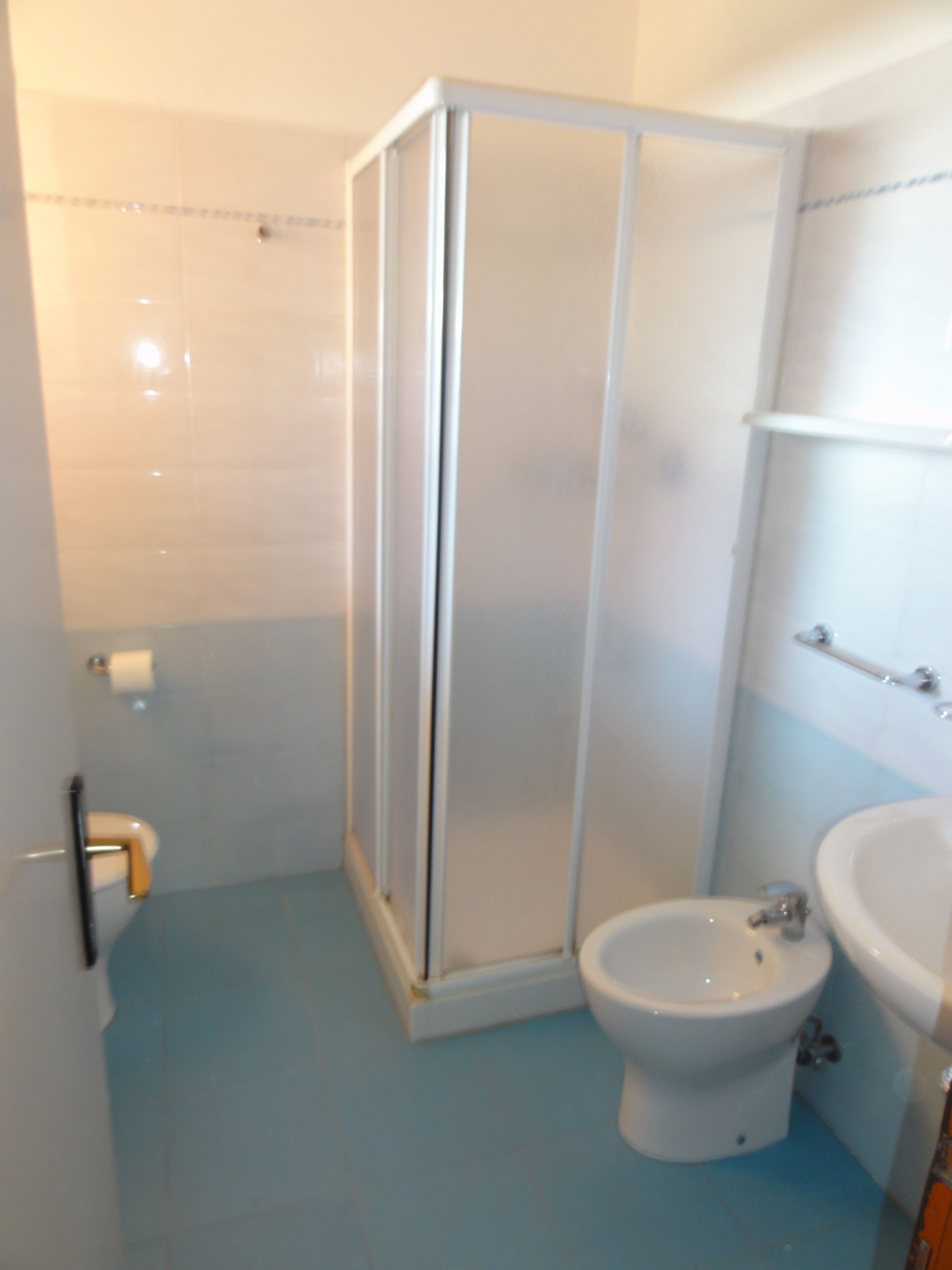 A bathroom with a shower enclosure, a toilet, and a sink.