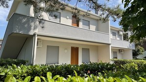 A two-story building with a flat roof, a front door, and two windows with shutters. - Flat in a House With Garden (San Michele al Tagliamento)