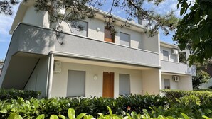 A two-story building with a flat roof, a front door, and two windows with shutters. - Comfy Flat With Pool in Bibione (San Michele al Tagliamento)