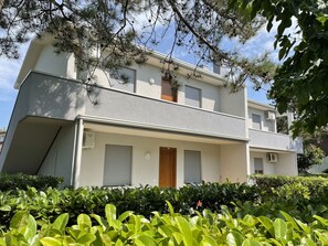 A two-story building with a flat roof, a front door, and two windows with shutters. - Comfy Flat With Pool in Bibione (San Michele al Tagliamento)