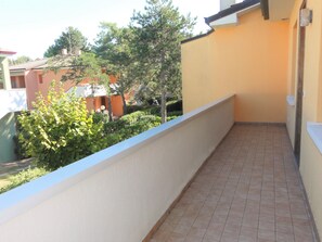 A balcony with a tiled floor and a low white wall. - Cozy Flat in a House With Pools (San Michele al Tagliamento)