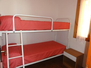 A bunk bed room with a wooden nightstand and a window with a curtain. - Cozy Flat in a House With Pools (San Michele al Tagliamento)