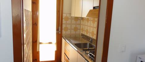 A compact kitchen with a sink, stove, and cabinets.