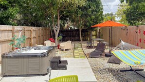 A backyard with a hot tub, lounge chairs, a hammock, and a patio table. - After Hours - Wilton Drive and Jacuzzi (Wilton Manors)