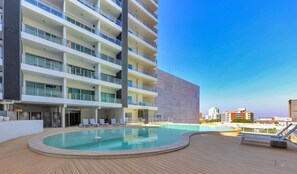 A modern hotel with a rooftop pool, multiple balconies, and a clear view of the city skyline. - Inner City Apt with Pool & Free Parking by Tropical BNB (Darwin City)