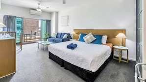 Hotellihuone, jossa on suuri sänky, työpöytä, tuoli, pieni pöytä, yöpöytä ja kattotuuletin.