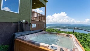 A hot tub on a balcony with a scenic view of a lake and mountains.