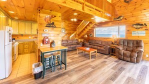 A wooden cabin interior with a kitchen, dining area, and living room.