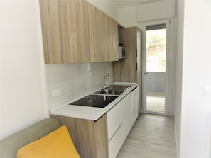 Eine kleine Küche mit Holdekor-Schränken, einer Edelstahl-Spüle und einer grauen Arbeitsplatte.