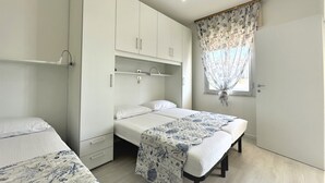 Una camera da letto con un letto, un armadio, un comodino e una finestra con tenda.
