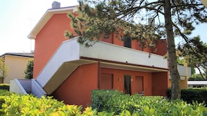 Ein Gebäude mit roter Fassade, einem geneigten Dach und einer Treppe, die zu einer oberen Ebene führt.