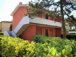 A building with a red facade, a sloped roof, and a staircase leading to an upper level. - Flat in a House With Shared Pool (San Michele al Tagliamento)