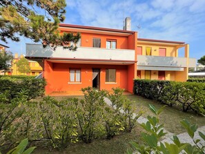 A two-story building with a flat roof and a red facade. - Flat in a House With Shared Pool (San Michele al Tagliamento)