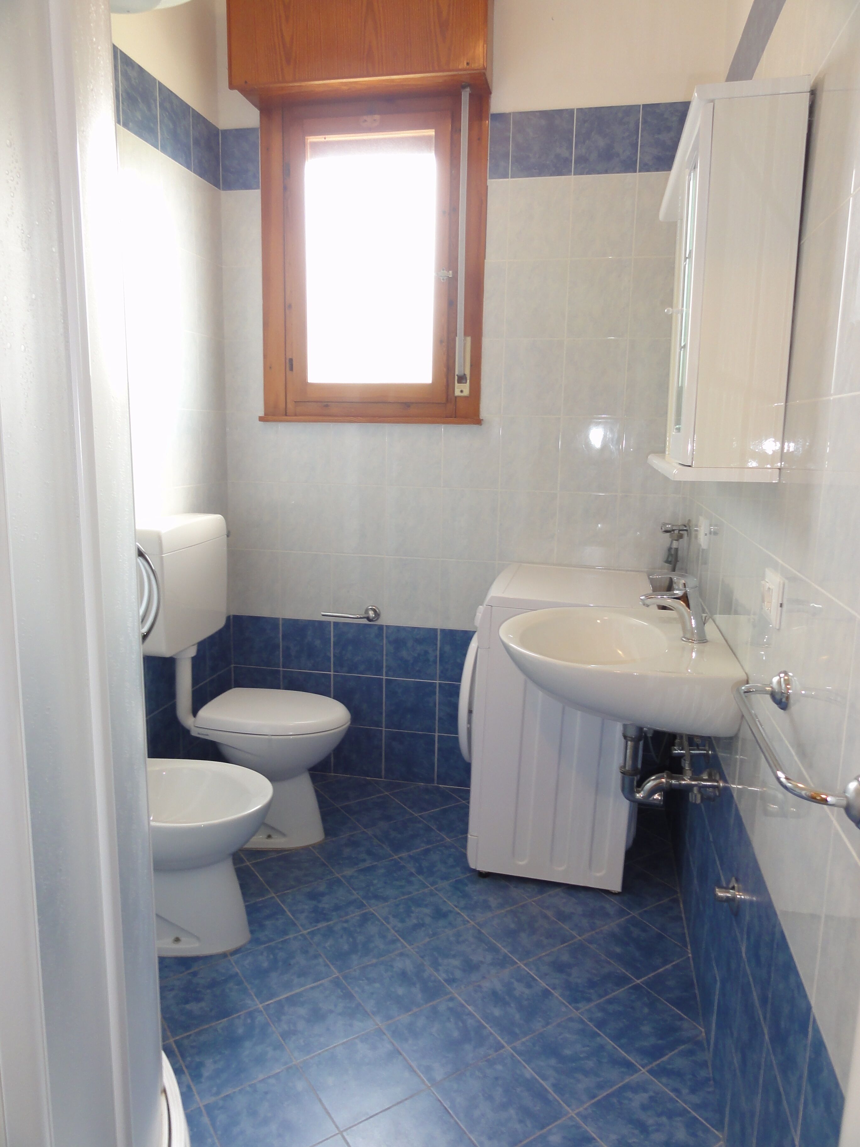 A bathroom with a toilet, sink, and cabinet.