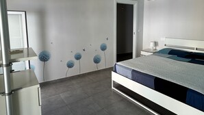 Una camera da letto con un letto, un comodino e una porta che dà su un'altra stanza.