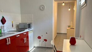 Una cucina moderna con mobili rossi, un piano di lavoro bianco e un'area pranzo con tavolo e sedia rossa.