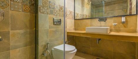 A bathroom with a glass shower enclosure, a white toilet, and a beige tiled wall with a decorative tile border.