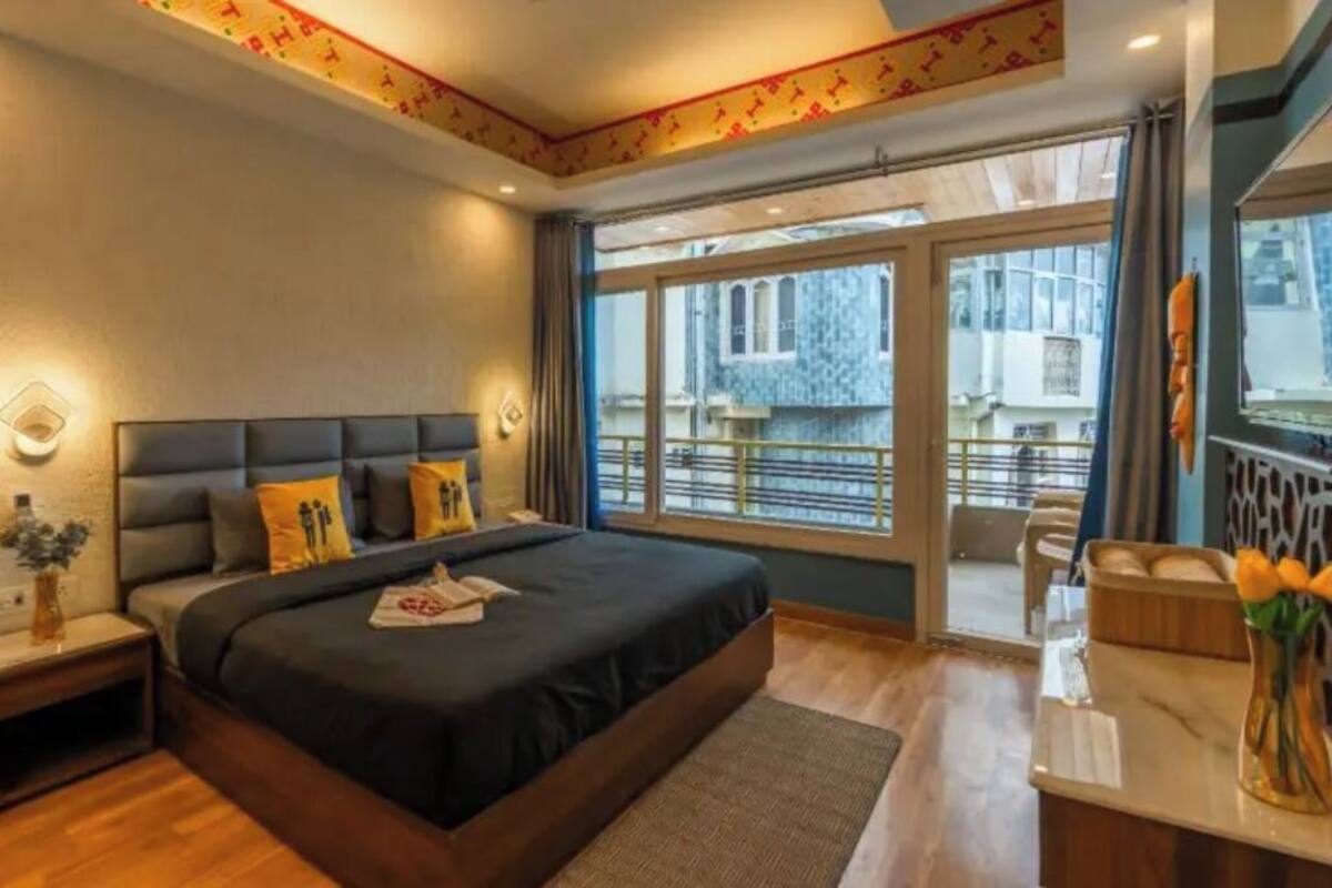 A modern hotel room with a large bed, a desk, and a view of the city.