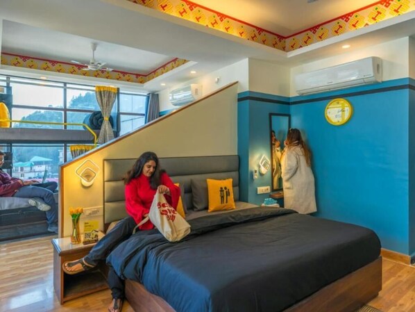 A hotel room with a bed, a desk, a chair, a window, and a staircase. - The Hosteller Mcleodganj, Bhagsu Waterfall (Dharamshala)