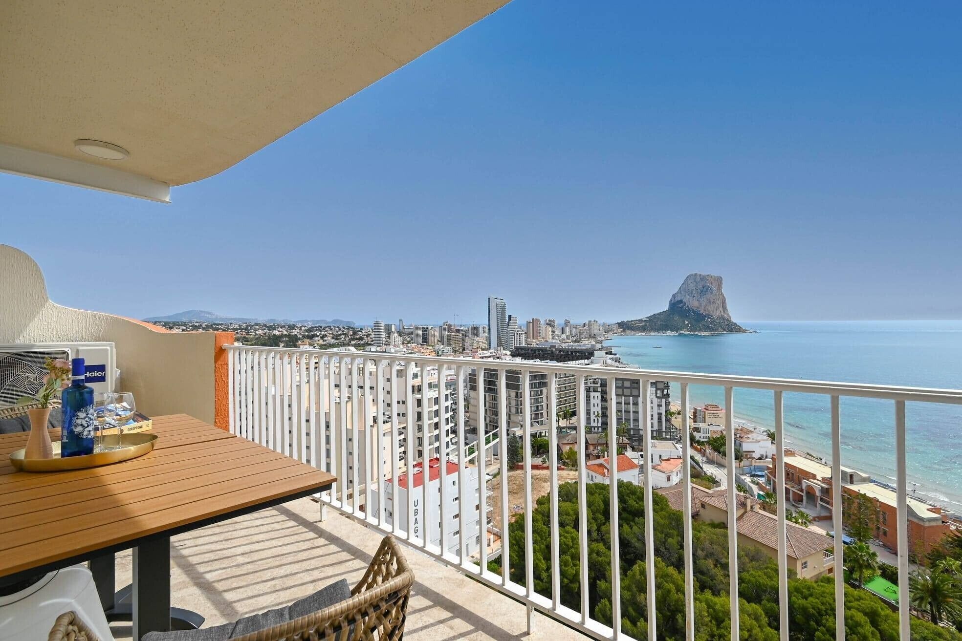 Een balkon met uitzicht op een kuststadsbeeld, inclusief een opvallende rotsformatie.