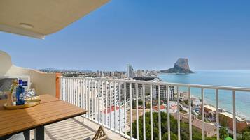 Een balkon met uitzicht op een kuststadsbeeld, inclusief een opvallende rotsformatie.
