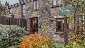 Una casa di pietra con un'insegna che riporta 'Gwyn' e una recinzione di legno sullo sfondo.