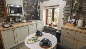Cucina con parete in pietra, forno a microonde, lavello e zona pranzo con tavolo e sedie.