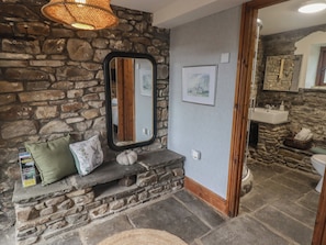 A stone-walled bathroom with a sink, a mirror, and a framed picture on the wall. - Gwyn Studio (Aberdare)