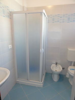 Un bagno con cabina doccia, lavandino, bidet e water.