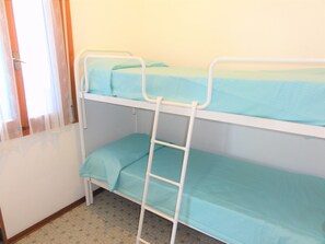 A bunk bed with a ladder, a window with curtains, and a patterned floor. - Colorful Flat in a Villa With Garden (San Michele al Tagliamento)