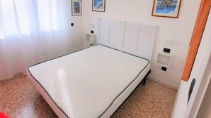 Un dormitorio con una cama individual, una silla roja y dos cuadros en la pared.