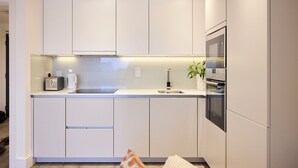 A modern kitchen with white cabinetry, a built-in microwave, and a coffee maker. - Streatham Hill Modern Flat with Balcony (London)
